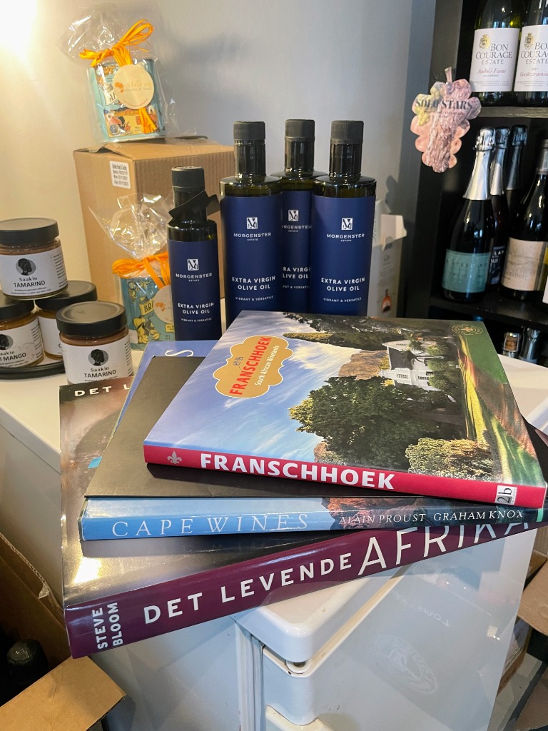 Bøgerne Det Levende Afrika, Cape Wines og Franschhoek stablet med Morgenster Estate olivenolie og Bon Courage vine
