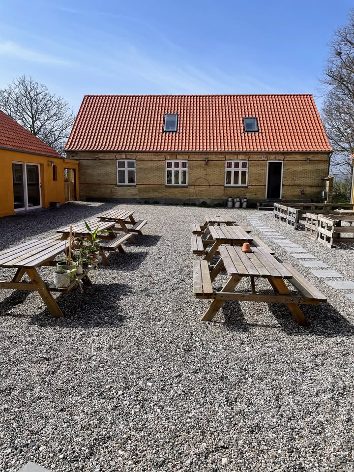 Den solrige gårdsplads med bænkesæt hos Ellens Have