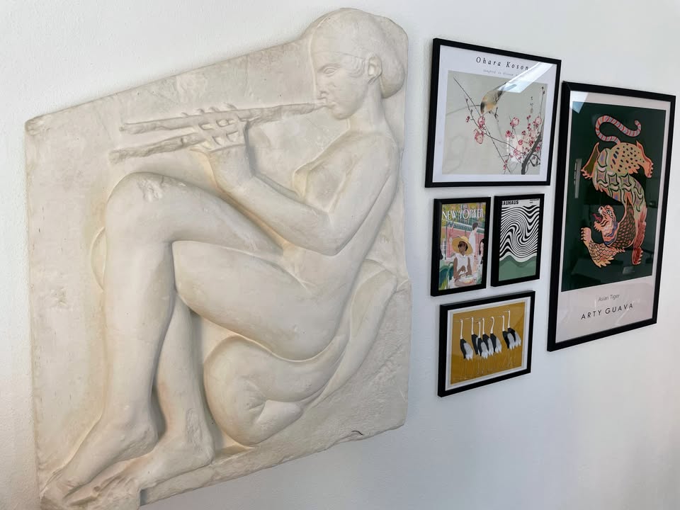 Gipsrelief af fløjtespillende kvinde og moderne kunstplakater