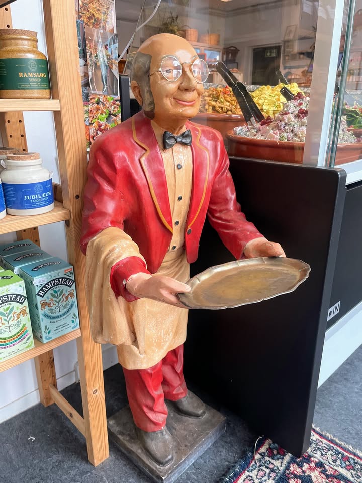 Rød vintagetjener-figur ved specialiteter og tehylder