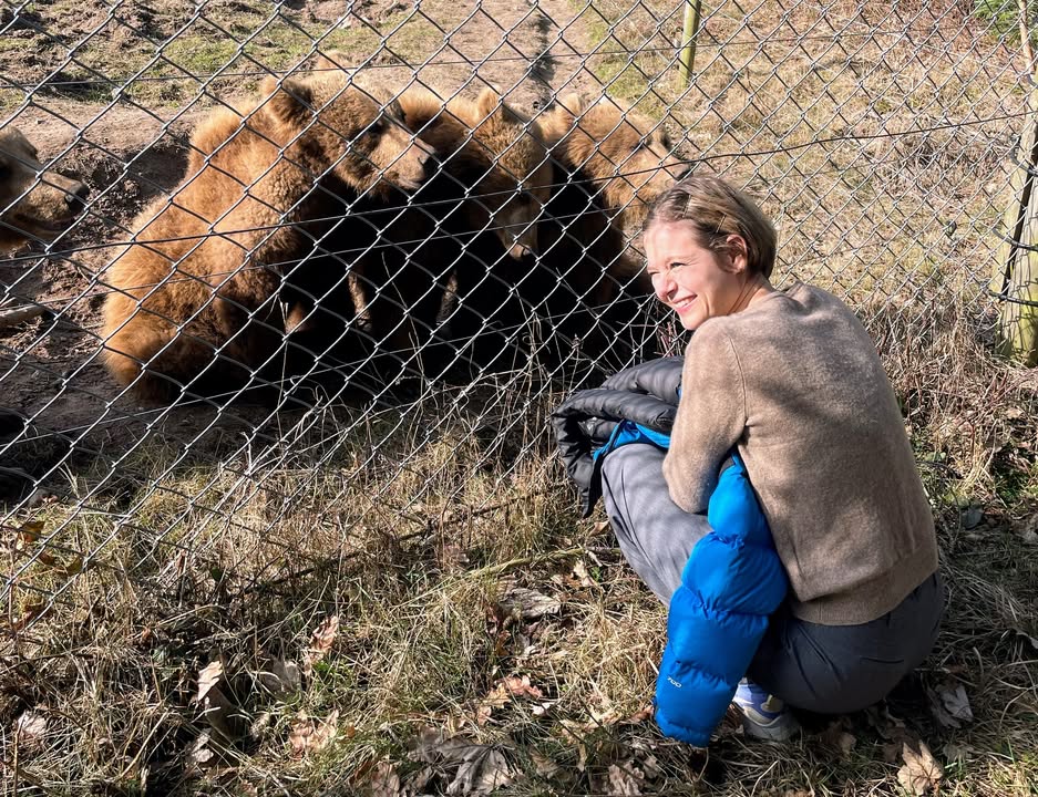 Anna Riis Lund på hug foran brunbjørneungerne ved hegnet