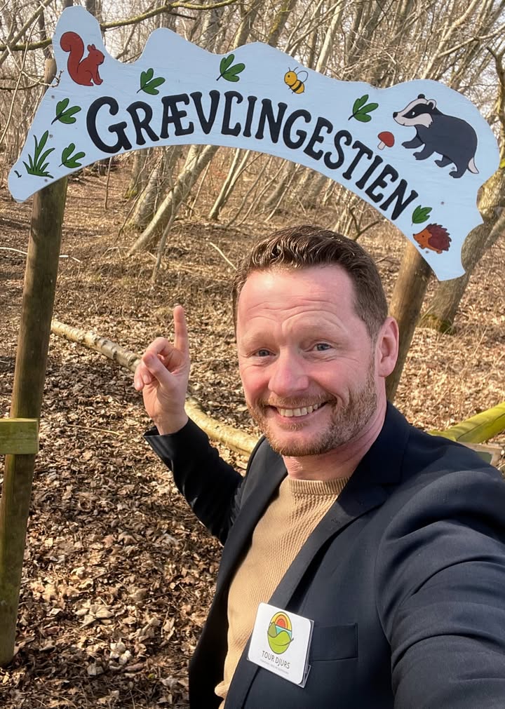 Jacob Lænsø peger op på Grævlingestien skiltet i skoven